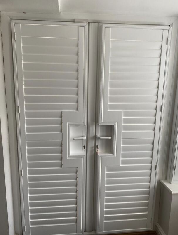 A pair of French doors fitted with shutters, each panel built with a handle cut-out